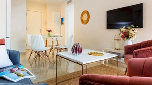 A modern living room with a flat-screen TV, a dining area with white chairs, and a red sofa. - Genteel Home Murillo II (Seville)