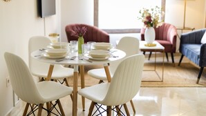 A dining area with a round table, white chairs, and a vase with flowers. - Genteel Home Murillo II (Seville)