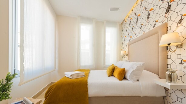 A hotel room with a bed, a bedside table with a lamp, and a window with curtains. - Genteel Home Murillo II (Seville)