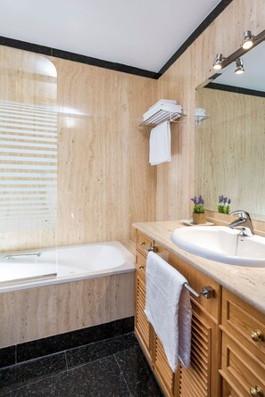 Een moderne badkamer met een badkuip, een wastafel en houten kastjes.