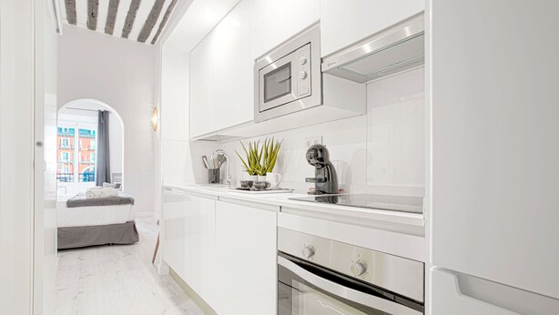 A modern kitchen with white cabinetry, a built-in oven, a microwave, and a coffee machine. - Apartment 1Bd With Balcony in Plaza Mayor Square. Plaza Mayor III (Madrid)