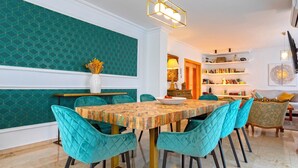 Un coin repas avec une table à motifs, des chaises de couleur turquoise et un vase rempli de fleurs.