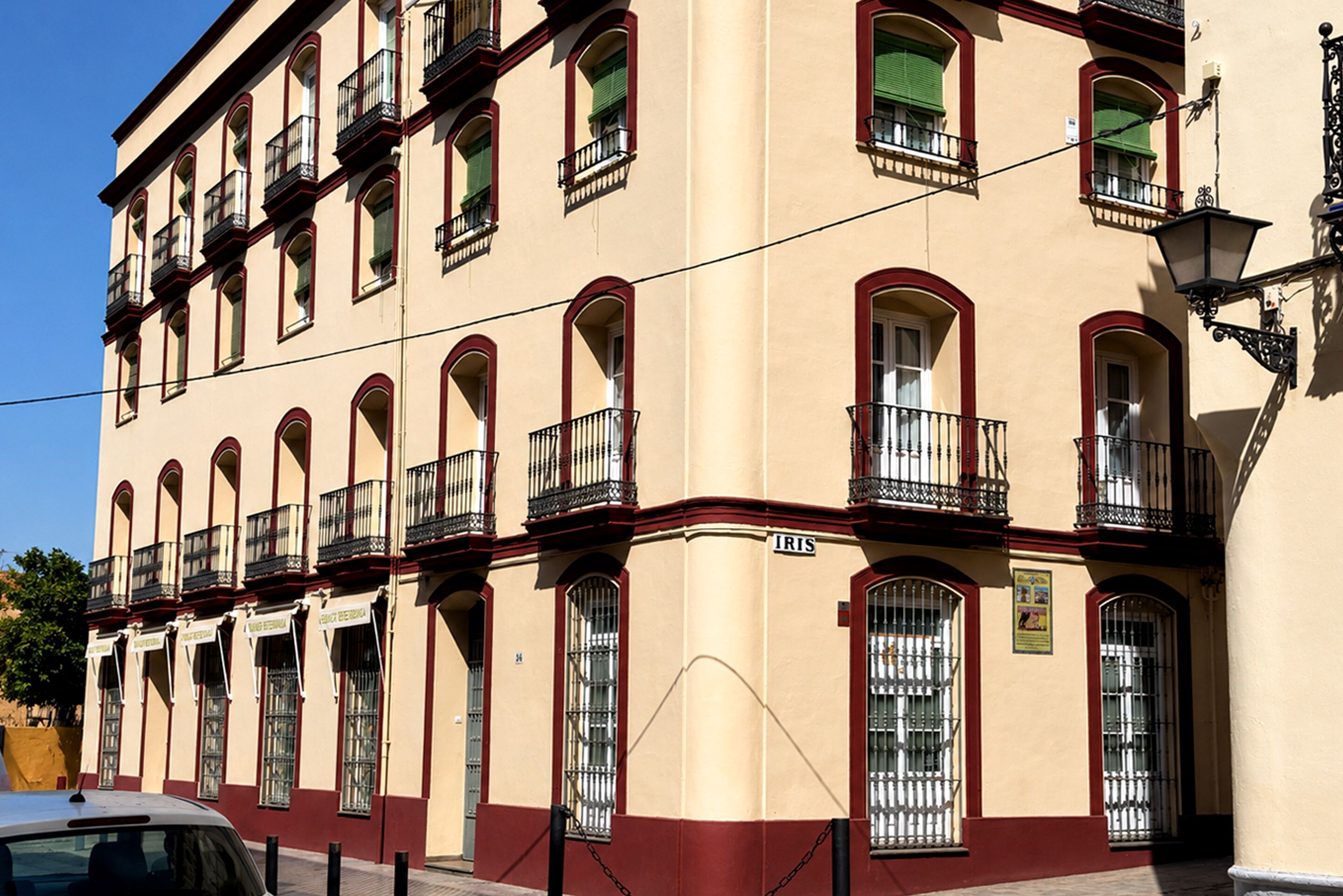 A multi-story building with arched windows and balconies, a sign reading 'IRIS,' and a chain barrier in front.