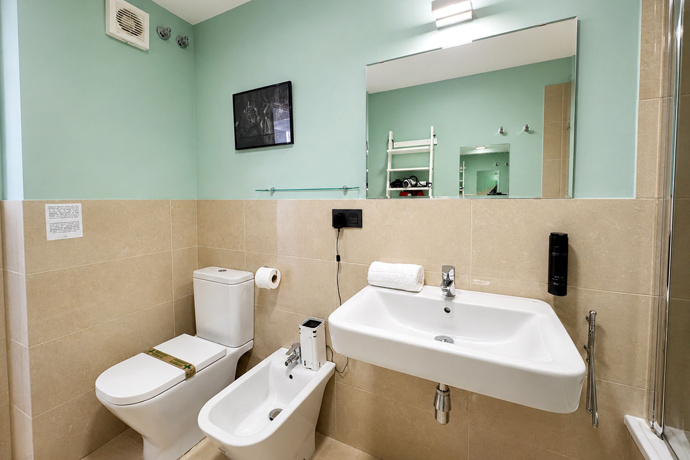 A bathroom with a toilet, bidet, sink, and a mirror.