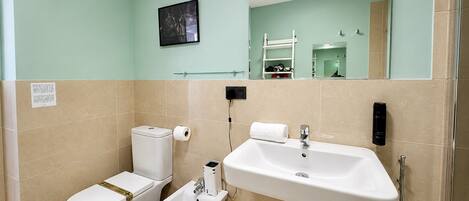 A bathroom with a toilet, bidet, sink, and a mirror.