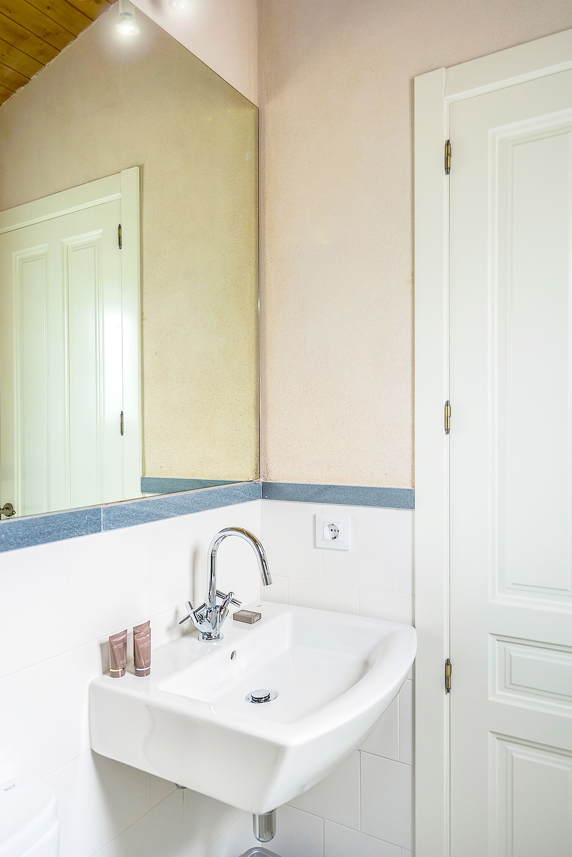 A bathroom with a white sink, mirror, and door.