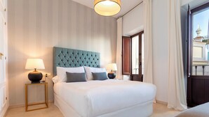 A neatly arranged hotel room with a large bed, two bedside tables with lamps, and a view through an open door. - Genteel Home Arfe Terrace II (Seville)