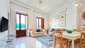 A living room with a sofa, coffee table, dining table, chairs, and a TV. - Genteel Home Arfe Terrace II (Seville)