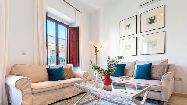 A living room with two sofas, a glass coffee table, and a red vase with plants. - Genteel Home Arfe Terrace II (Seville)