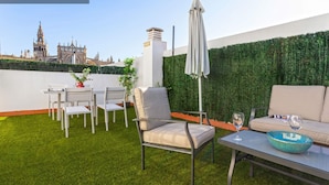 A rooftop terrace with a view of a historic building, a green wall, and outdoor furniture. - Genteel Home Arfe Terrace II (Seville)