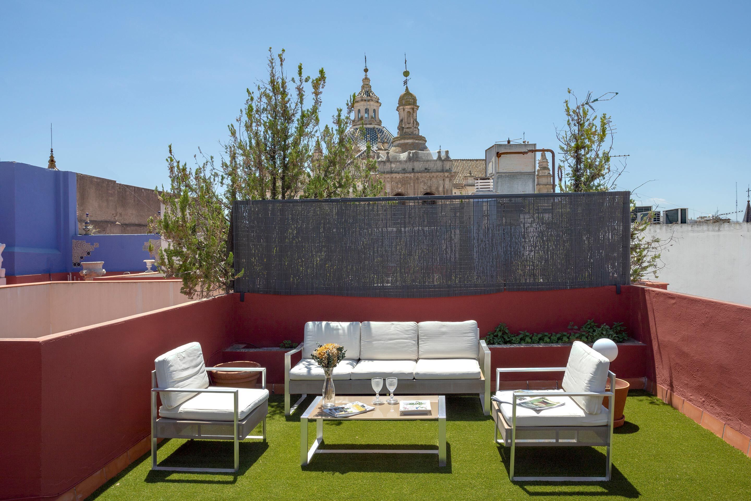 Una terrazza sul tetto con un divano bianco, un tavolino da caffè e un vaso decorativo.