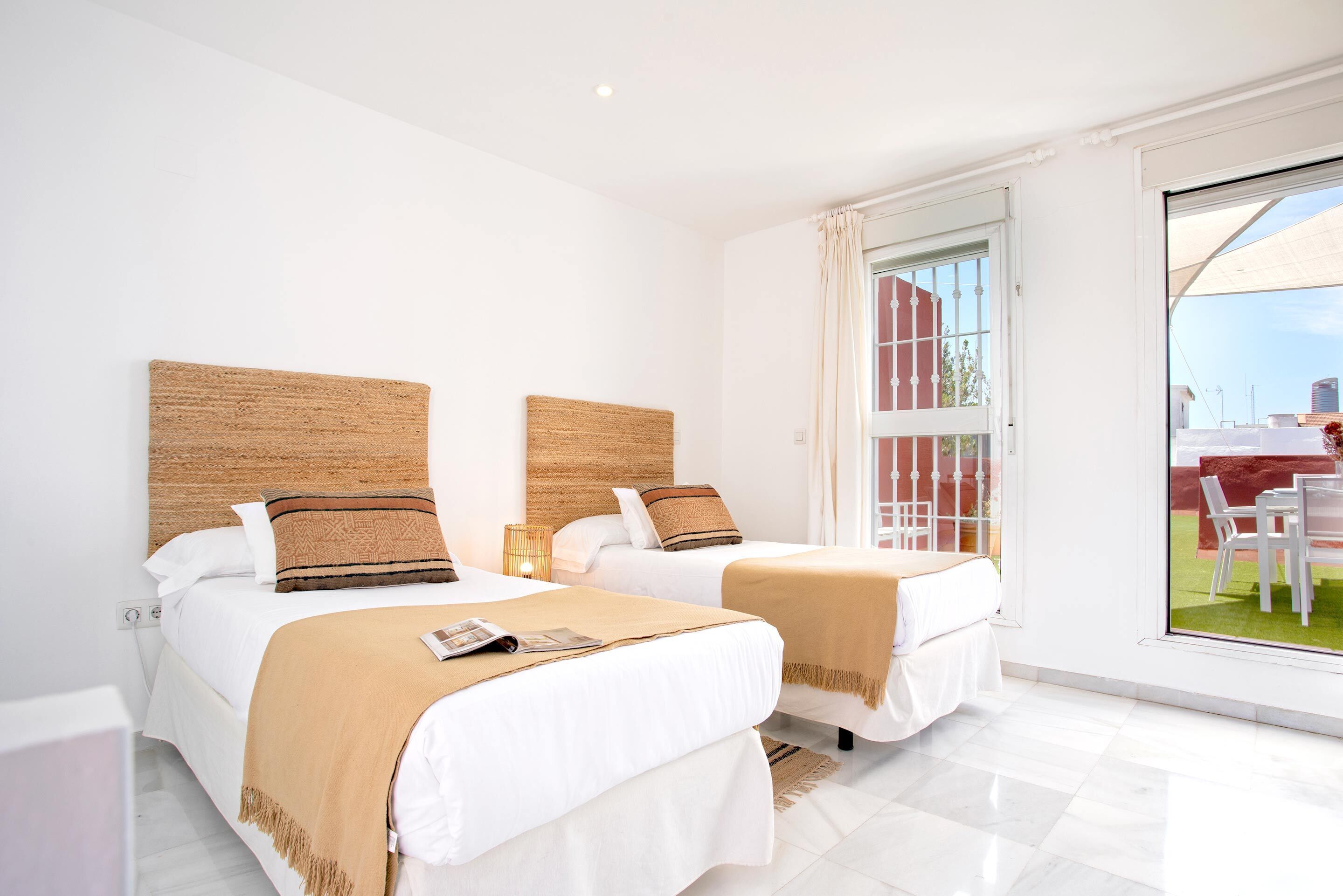 A hotel room with two beds, a large window, and a view of the outside.