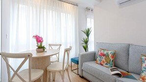 A living room with a grey sofa, a round wooden table with chairs, and a potted plant. - Genteel Home Santo Cristo (Granada)