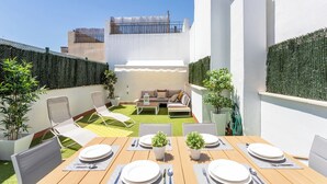 A rooftop patio with a dining table set for four, surrounded by lounge chairs and a sofa. - Genteel Home Francos Terrace VI (Seville)