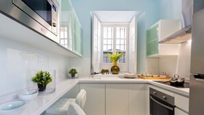 A modern kitchen with white cabinets, a built-in oven, and a window with blinds. - Genteel Home Argote de Molina (Seville)