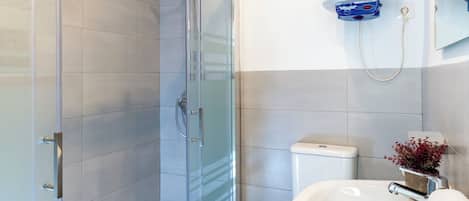 A modern bathroom with a glass shower enclosure, a white sink, and a wall-mounted light fixture.
