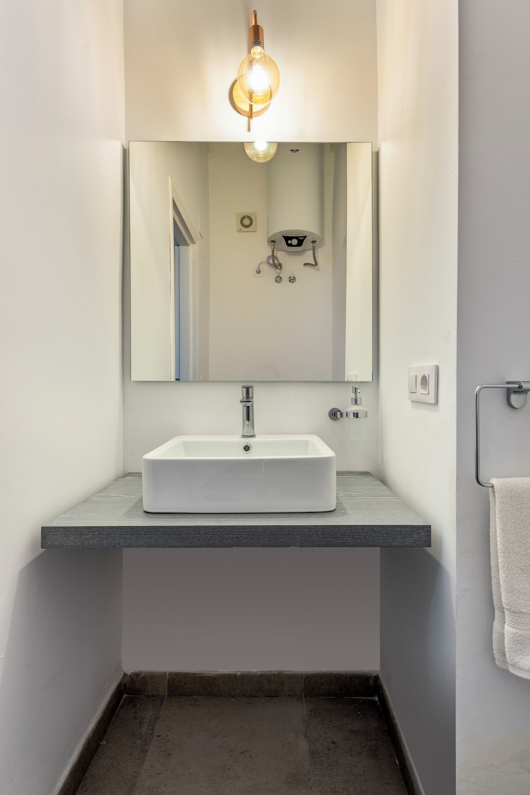 Un baño moderno con un lavamanos rectangular, un espejo encima y una lámpara.