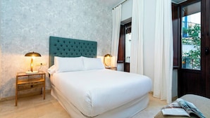 A neatly arranged bedroom with a large bed, two bedside tables with lamps, a window with curtains, and a view of the outside. - Genteel Home Arfe Terrace (Seville)