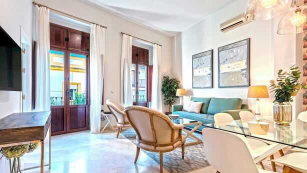 A modern living room with a glass dining table, a sofa, and a TV. - Genteel Home Arfe Terrace (Seville)