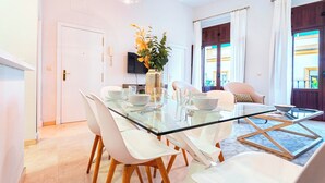 A modern dining area with a glass table, white chairs, and a vase with flowers. - Genteel Home Arfe Terrace (Seville)