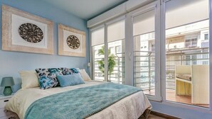 Ein Schlafzimmer mit einem Bett, einem Nachttisch, einer Lampe und zwei gerahmten Kunstwerken an der Wand.