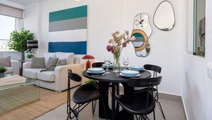 A modern living room with a dining area, featuring a sofa set, a coffee table, a dining table with chairs, and a large abstract painting on the wall. - Genteel Home Campana (Seville)