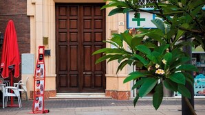 A building with a large wooden door, a red umbrella, and a signboard with images of food items.