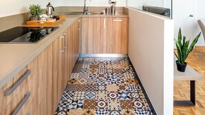 A modern kitchen with wooden cabinets, a patterned tile floor, and a built-in stove.