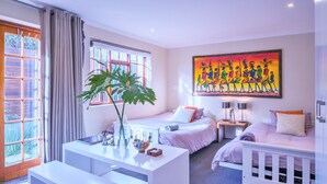 A modern bedroom with two beds, a white desk, a large window, and a colorful painting on the wall. - Sun & Sea Family Villa (Cape Town)