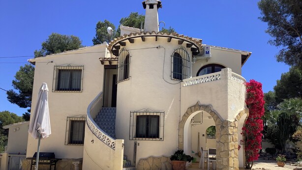 Een villa in mediterrane stijl met een zwembad, een overdekt terras en een stenen boog.