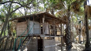 A rustic wooden structure with a thatched roof, surrounded by dense foliage. - Unspoiled South Gambian Paradise '' Pure Nature Treehouse '' (Kartung)