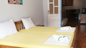 A double bed with two white pillows and a yellow bedspread in a room with wooden flooring and a white door. - Posejdon (Ulcinj)