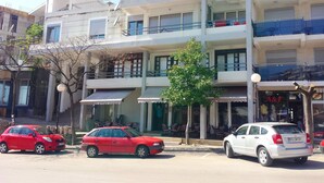 A multi-story building with balconies, a cafe, and parked cars. - Posejdon (Ulcinj)