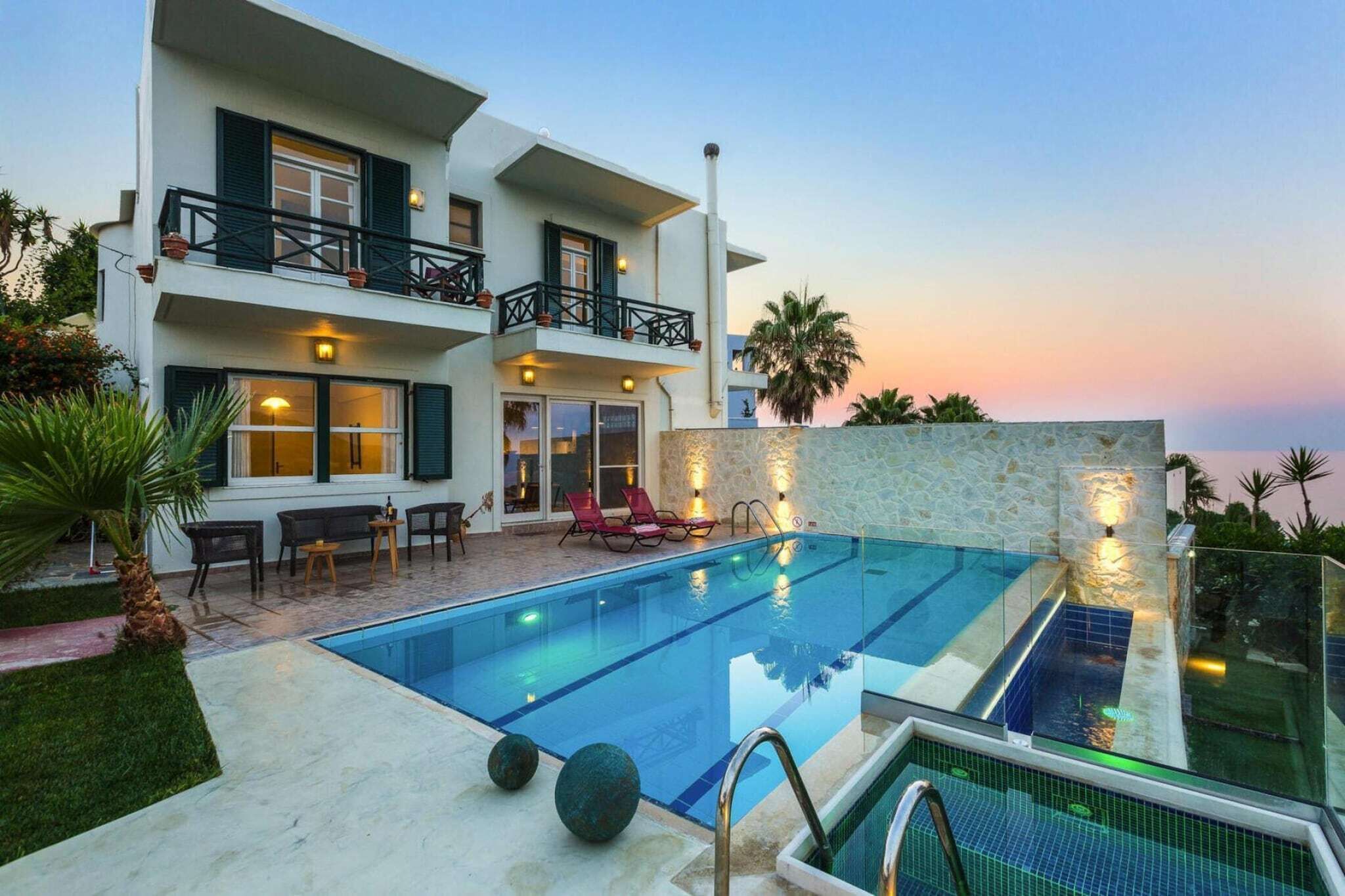 A modern two-story building with a swimming pool, outdoor seating, and a stone wall.