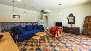 Un soggiorno con un divano blu, una poltrona rossa, un tavolo in legno e una scala che conduce a un piano superiore.