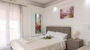 A bedroom with a large bed, a nightstand, a window with sheer curtains, and two wall-mounted artworks. - Petrakis Beach (Corfu)