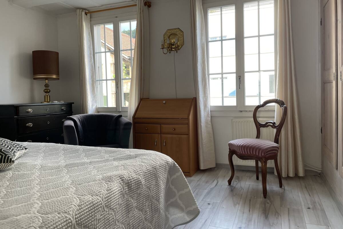 A bedroom with a bed, a desk, a chair, and a dresser.