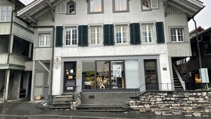 Un bâtiment à deux étages doté d’une devanture de magasin, d’un escalier menant à l’entrée et d’un mur de pierre à l’avant.