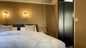 Une chambre d’hôtel avec un grand lit, deux lampes fixées au mur et une porte sur le côté droit.