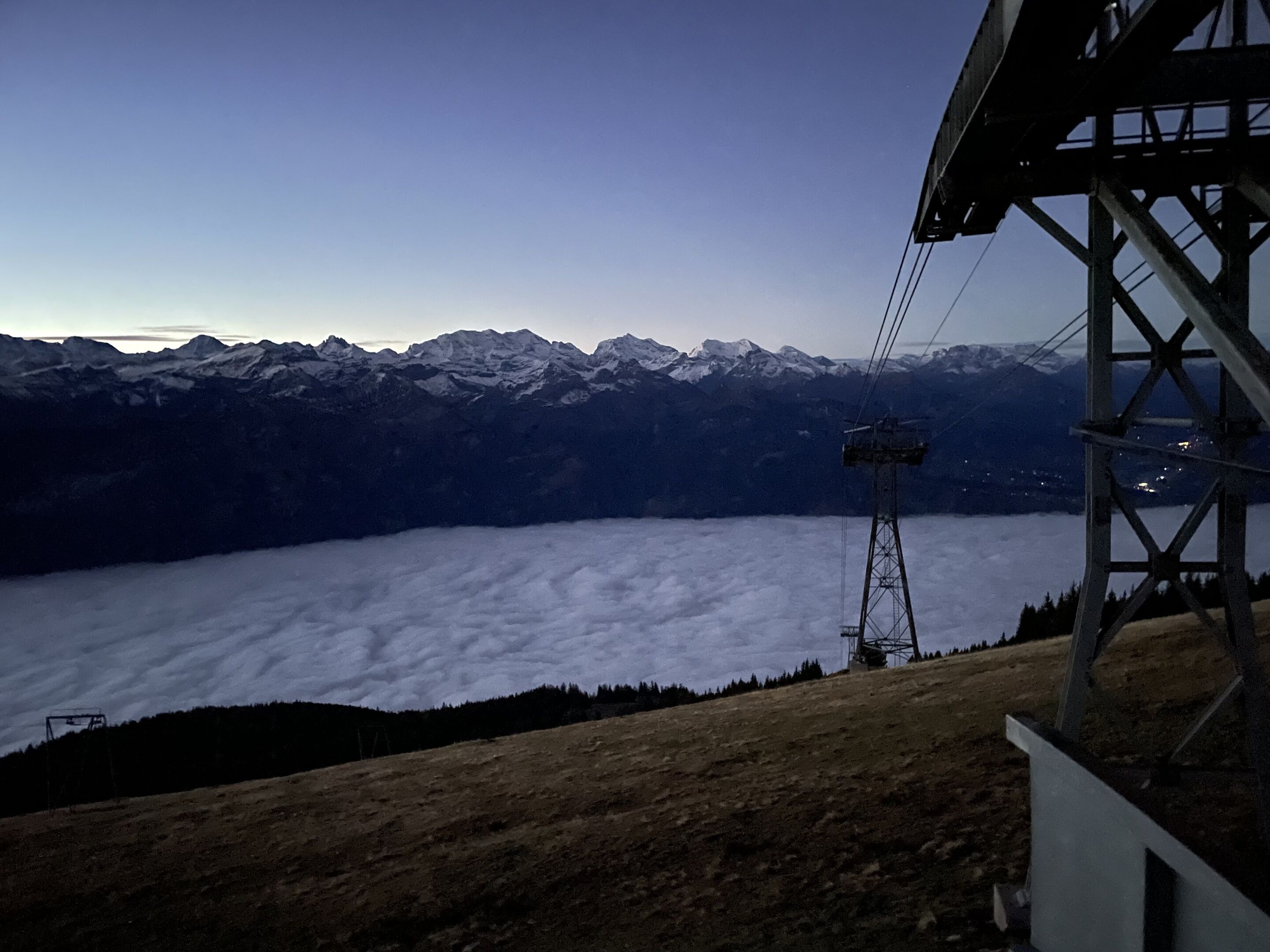 A mountain landscape with a ski lift and a view of snow-covered peaks.