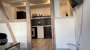 Une cuisine moderne avec des poutres en bois, un lave-vaisselle et un téléviseur à écran plat fixé au mur.