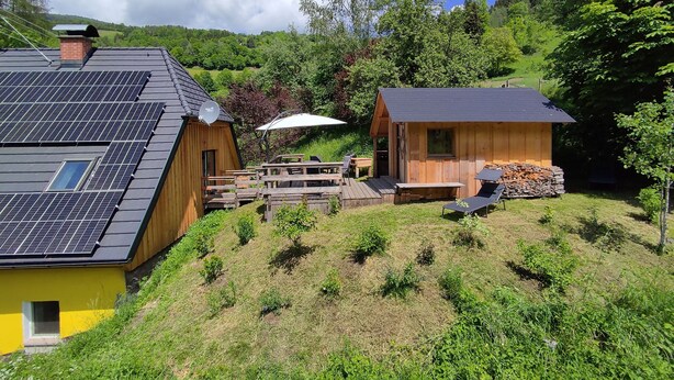 A cabin with solar panels, a wooden deck, and a small outdoor seating area. - Yellow house: secluded location, sauna hut, terrace, fenced - vacation with dog (Bodendorf)