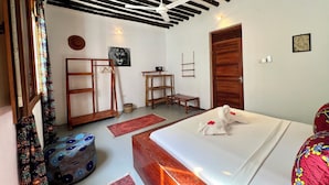Un dormitorio con cama, muebles de madera, ventilador de techo y una puerta.