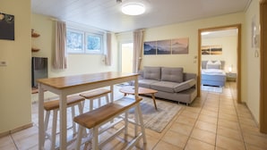 A spacious living area with a wooden dining table, a sofa, and a bed in the background. - Awad's Yellow Apartment (Rust)
