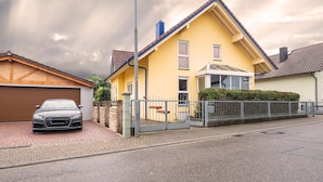 A yellow house with a garage, a gated driveway, and a parked car. - Awad's Yellow Apartment (Rust)