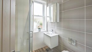 A modern bathroom with a shower, a window, a sink, and a mirror. - Host & Stay | Number 2 at Pannett Apartments (Whitby)