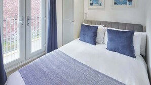 A hotel room with a bed, a wardrobe, and a balcony. - Host & Stay | Number 2 at Pannett Apartments (Whitby)