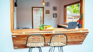 A wooden reception desk with a laptop, a fruit bowl, and two wicker chairs. - Alloro Jungle Villas (Cahuita)