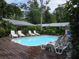 Una piscina al aire libre, sombrillas, sillones reclinables de piscina