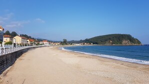 Eine Küstenstraße mit einer Steinmauer an einer Seite und einem Strand daneben.